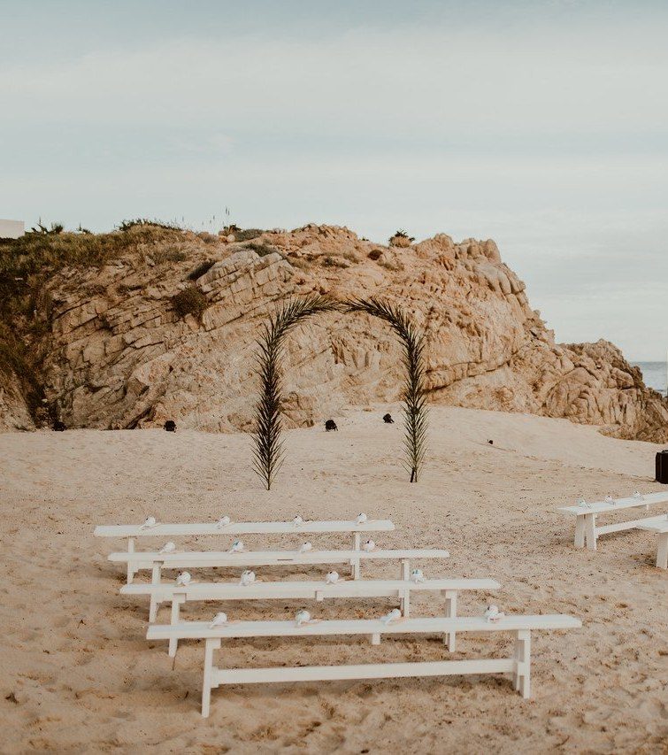 Wedding arch with flowers and white benches on the beach