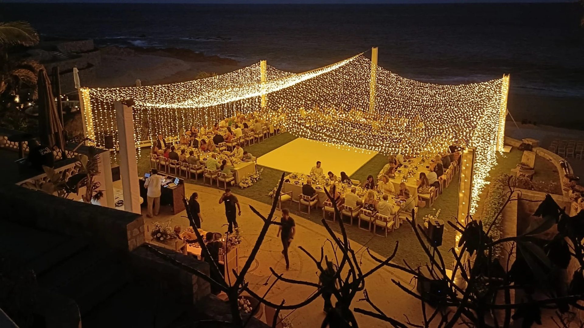 Seaside dinner and dance floor under a canopy of lights at night