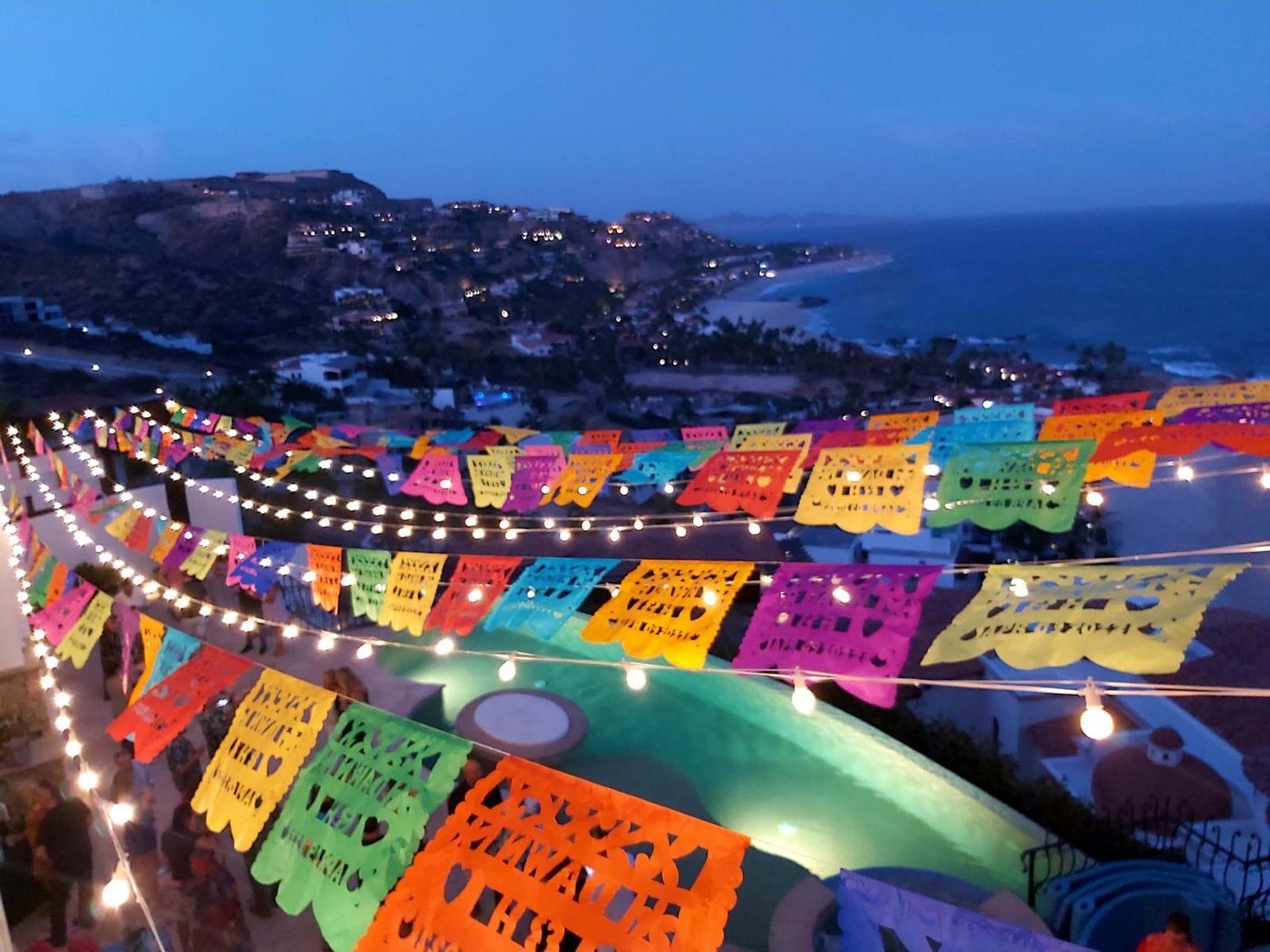 Mexican fiesta with colorful papel picado over the pool at night