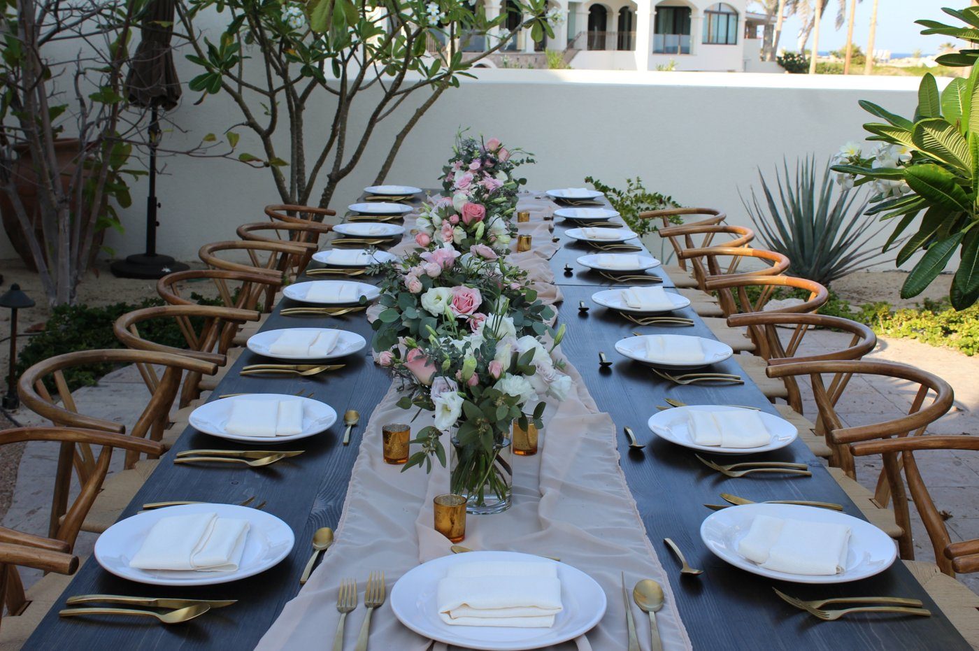 Long dinner table with floral centerpieces on a villa terrace