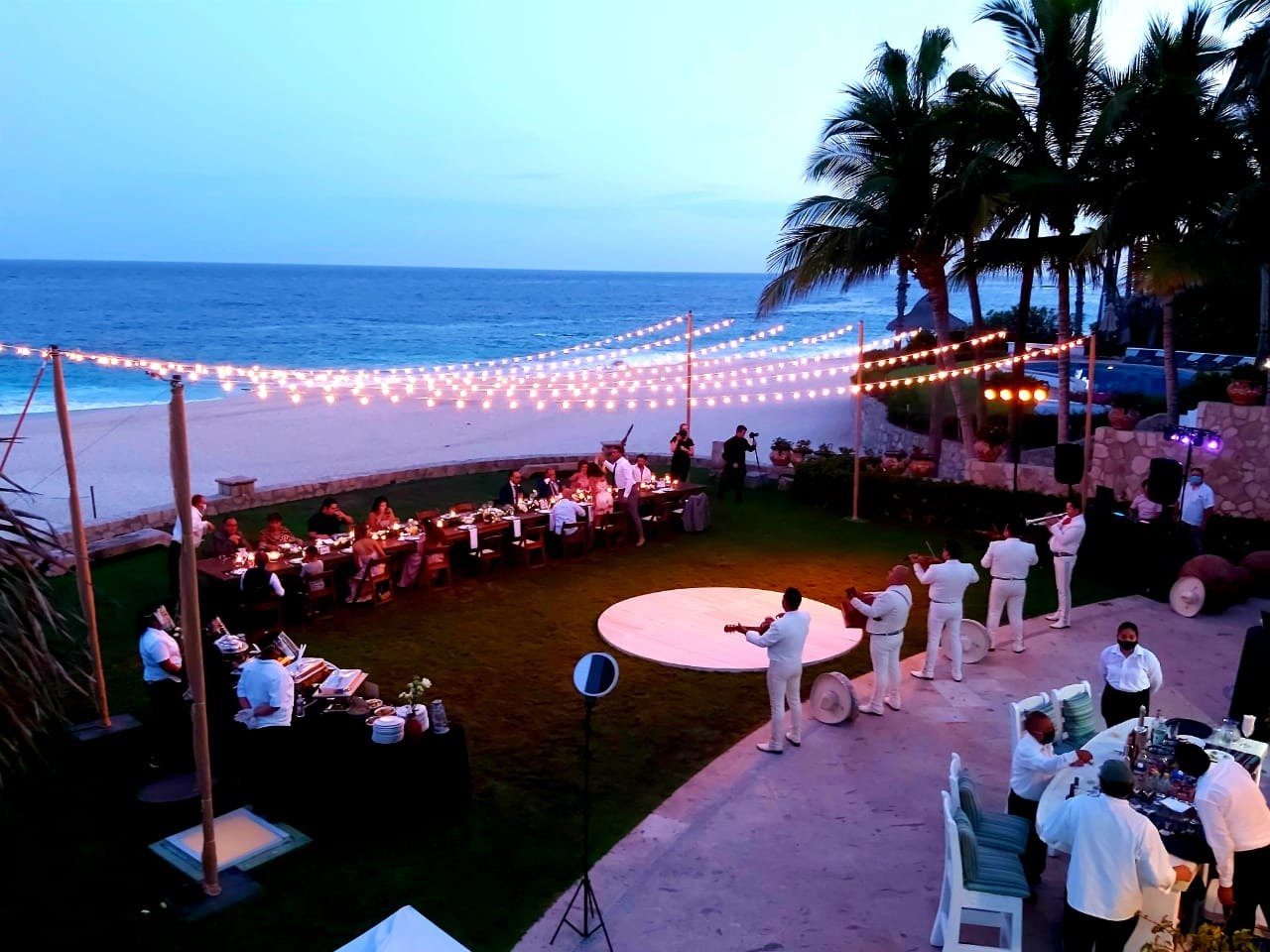 Mariachi band and lit dance floor at a seaside party at night